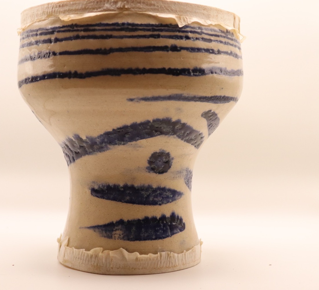 Reverse of a finished ceramic darbuka with blue bands and marks